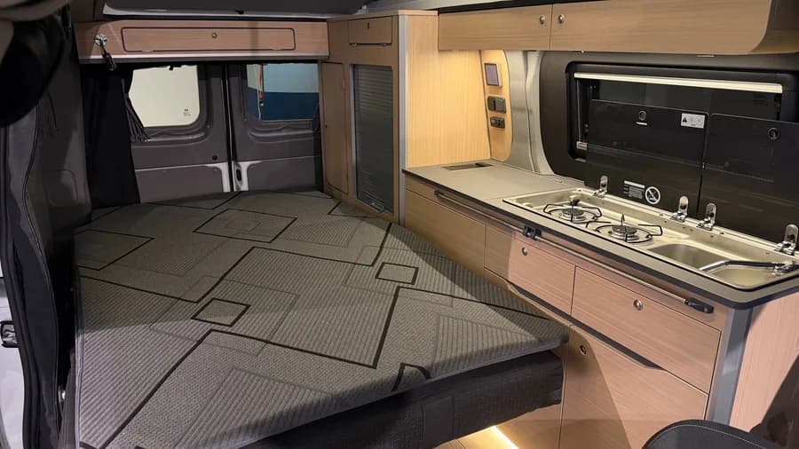 Wide view of the made-up bed with the Dometic combination hob and sink on the right