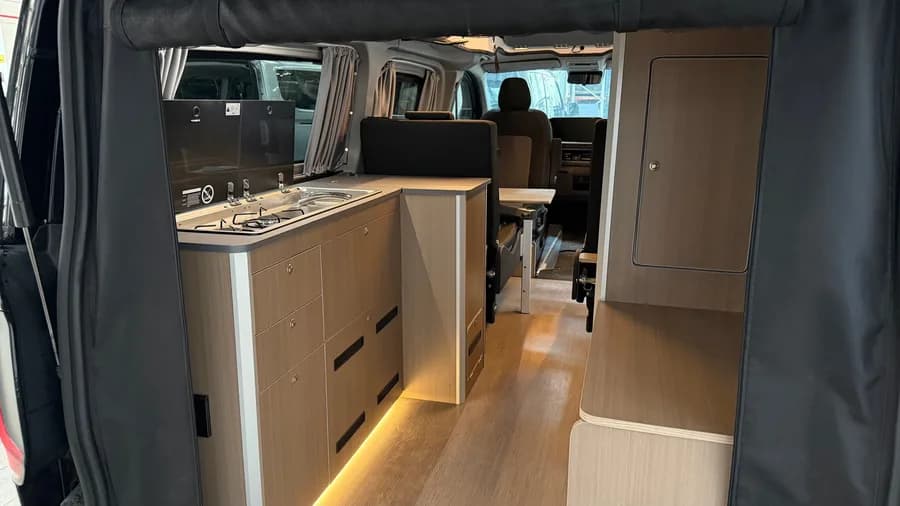 Interior with the Dometic hob and sink unit and wooden furniture lit by LED strips