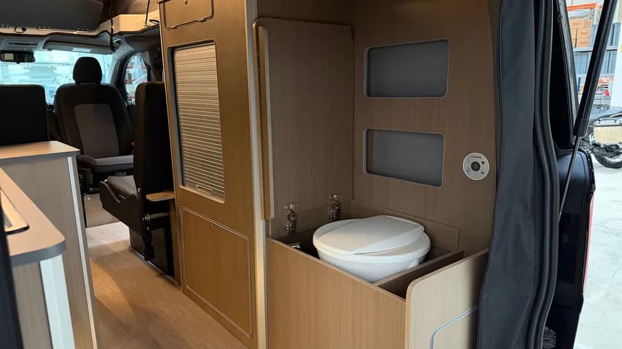 Dometic cassette toilet with its cabinet open, next to the roller-shutter wardrobe