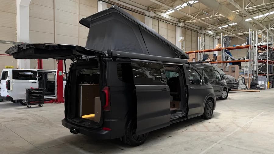 Rear three-quarter view with the tailgate and pop-up roof open and the Thule awning fitted