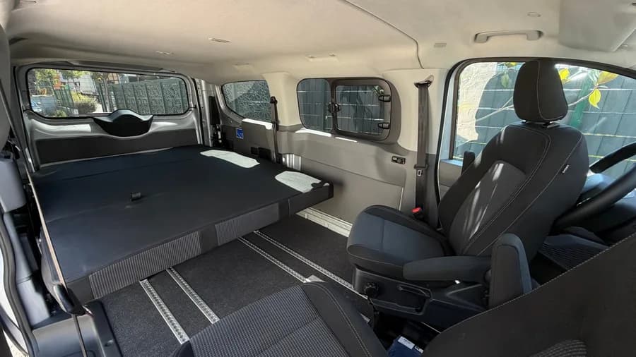 Interior with the STIDE seat system folded into a wide bed and the aluminium floor rails
