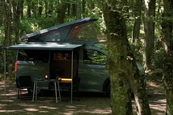 Orman kampında pop-up tavanı ve tentesi açık Demonte Karavan campervan, ağaçların arasından kuşbakışı