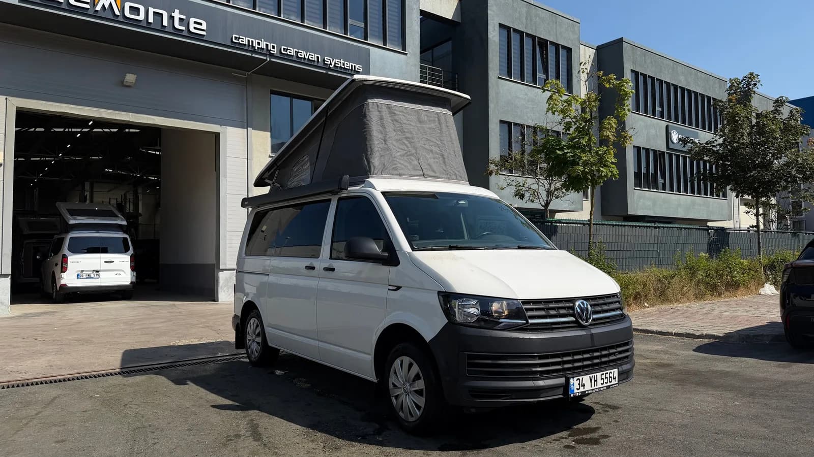 White VW Transporter T6 Cappadocia outside the Demonte Caravan facility with the SCA roof raised