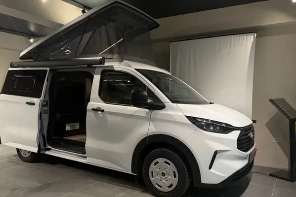 White Ford Transit Custom Assos in the showroom with the SCA pop-up roof raised and side door open