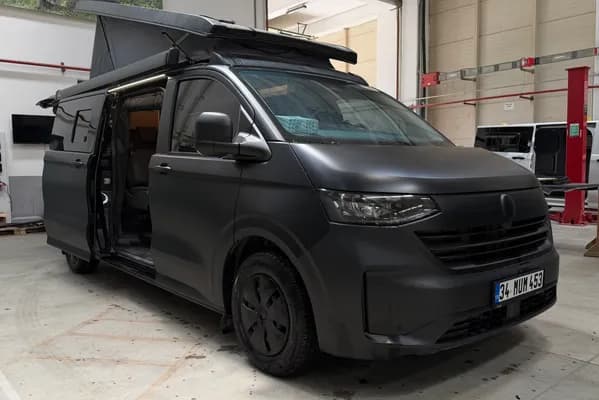 Matte black Volkswagen Transporter 4x4 Olympos in the workshop with the SCA pop-up roof and side door open
