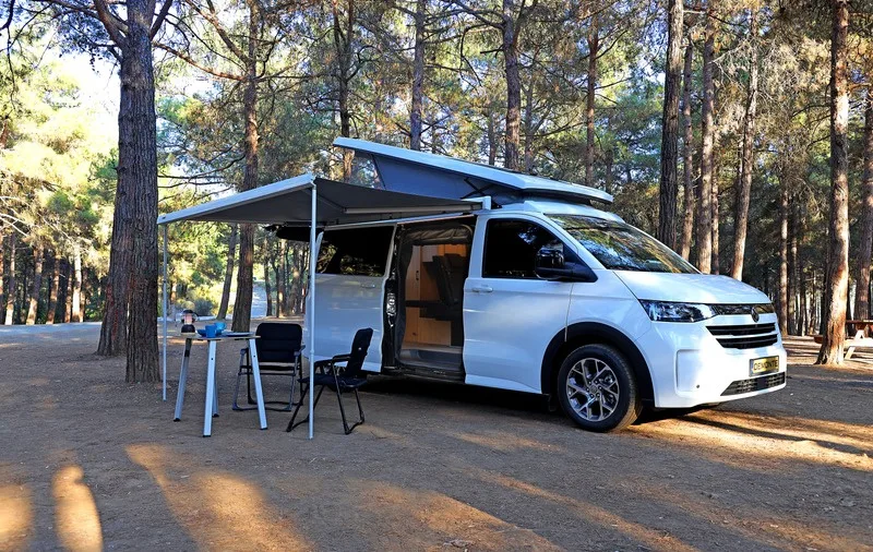 The Efes camp in the pine forest with the table and chairs under the awning and the sliding door open