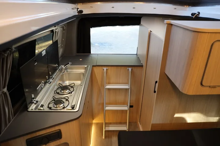 The kitchen of the Efes with its two-burner hob, fold-out worktop extension and the ladder to the roof bed