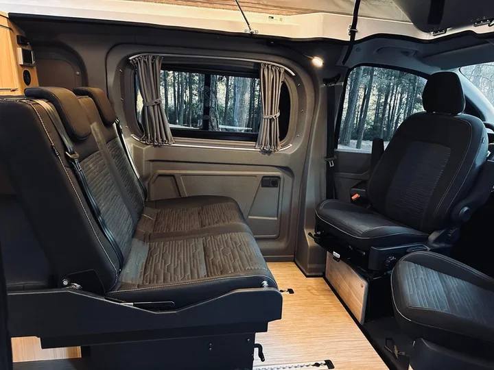 The seating area of the Efes with swivelling front seats, the rear bench and a wooden floor