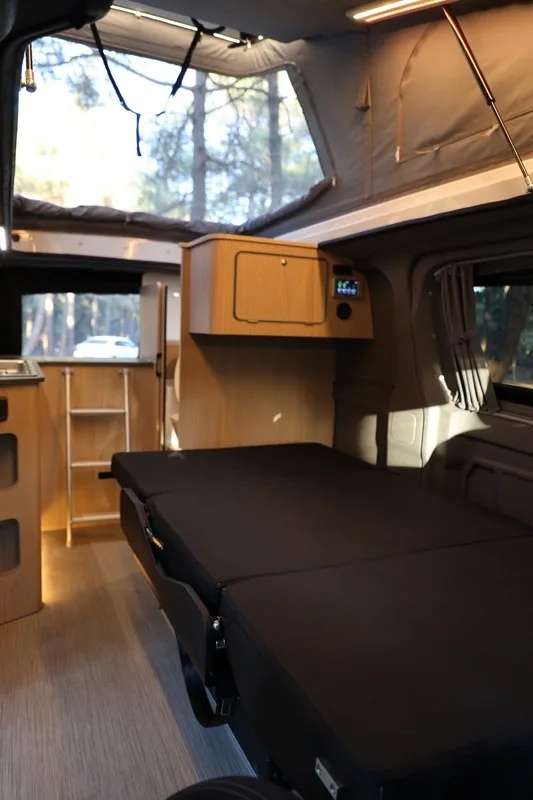 The rear bed of the Efes made up, flanked by wooden cabinets and curtained windows