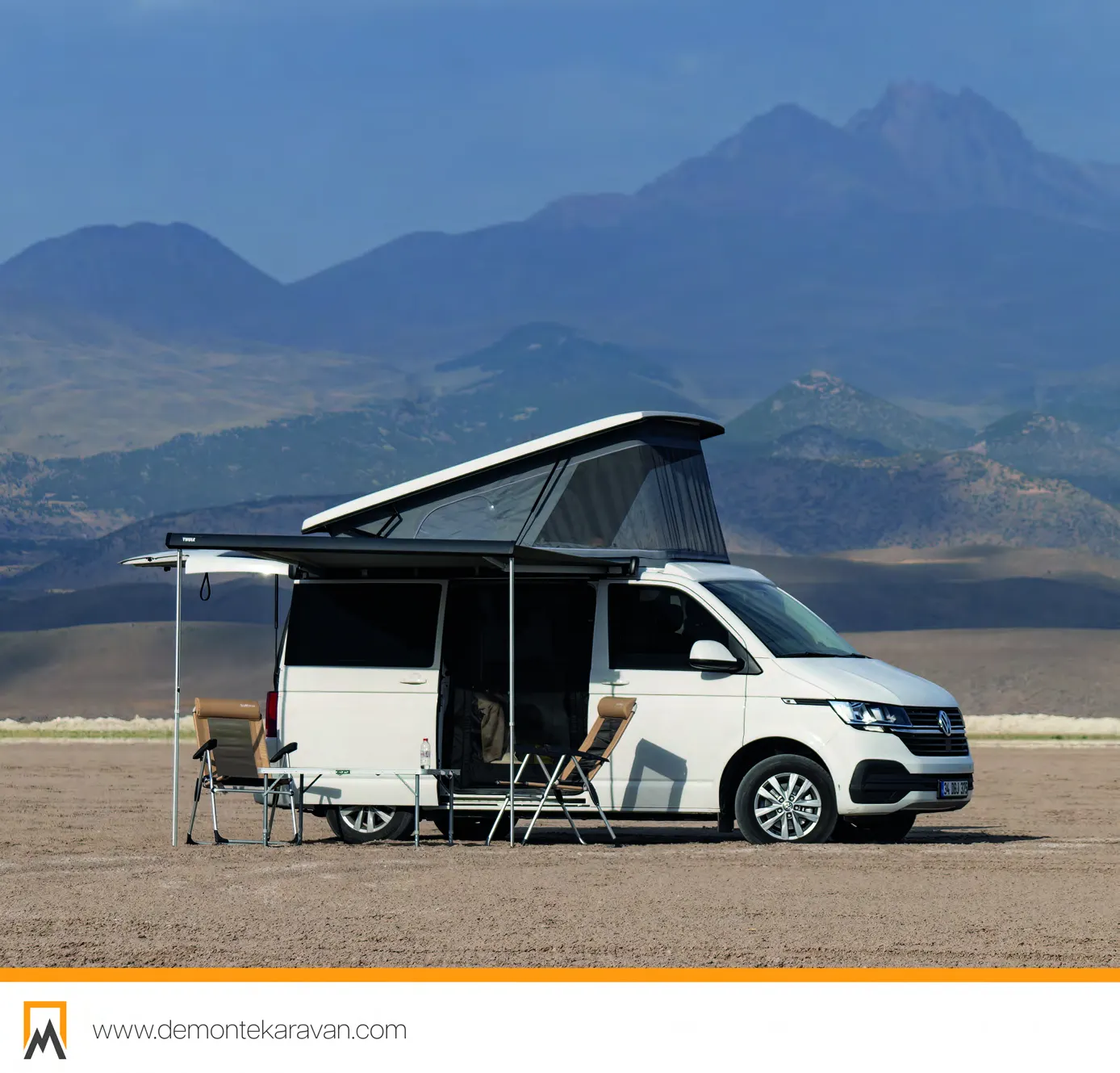 Demonte Karavan 2026 catalogue, page 16: a white VW Transporter with its awning out and camp set up in front of a mountain range