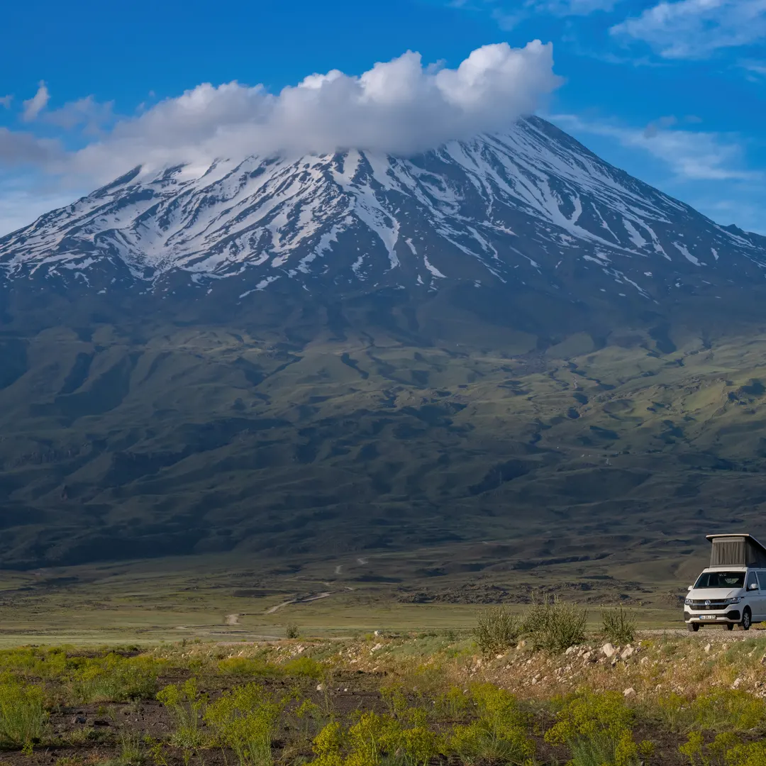 Der schneebedeckte Gipfel des Ararat über der grünen Ebene mit einem Demonte-Camper